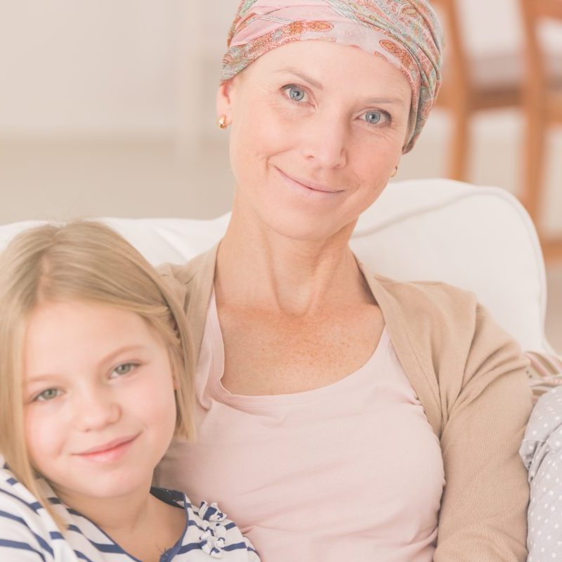 Woman with cancer sitting on sofa with her daughter